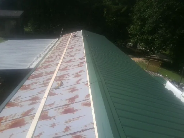 Old rusted panels beside newly installed green metal roofing — Wind Damage Roof Repair by Roofing Brothers in Palm Beach
