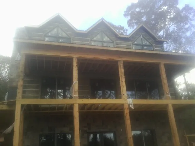 Dormers and porch framing on a large log home under construction — Roof Coating work by our crew in Palm Beach