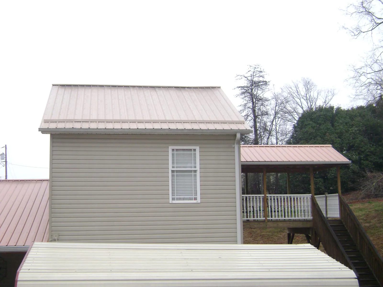 Tan metal roofs on a two story addition and attached porch, from a Roof Replacement job in Palm Beach